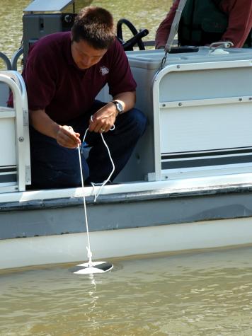 Tony Thorpe demonstrates how to use a Secchi disk to measure the clarity of lake water.University of Missouri