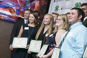 Students holding scholarship certificates pose for a photo.