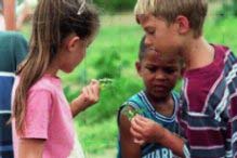 Three kids looking closely a plants they are holding