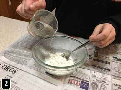 Water being poured into a bowl of flour and stirred.