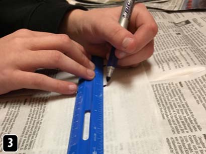 Small dots being drawn on a strip of toilet paper with the aid of a ruler.