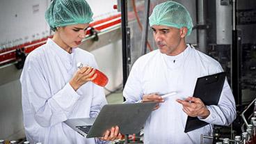 Employees checking bottled drinks in manufacturing plant.