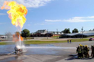 Fire fighters spring a burning gas tank with water.