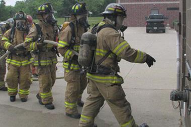 Fire fighters approaching an exterior door to a building.