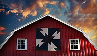 A blue and white quilt on the front of a barn