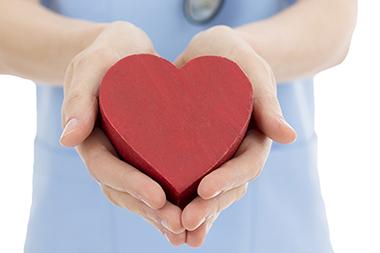 A nurse holding a wooden heart in her hands