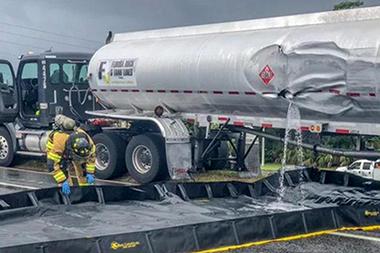 Gasoline tank truck with a fire fighter containing a spill.