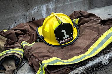 A firefighter suit laying on a wet street with the helmet on top.