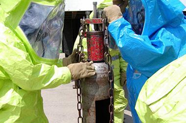 Two people in hazmat suits working with a chlorine device.