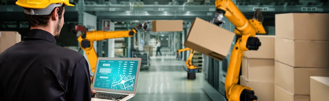 A man working on a laptop in a factory.